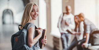 Student wearing backpack and holding textbooks